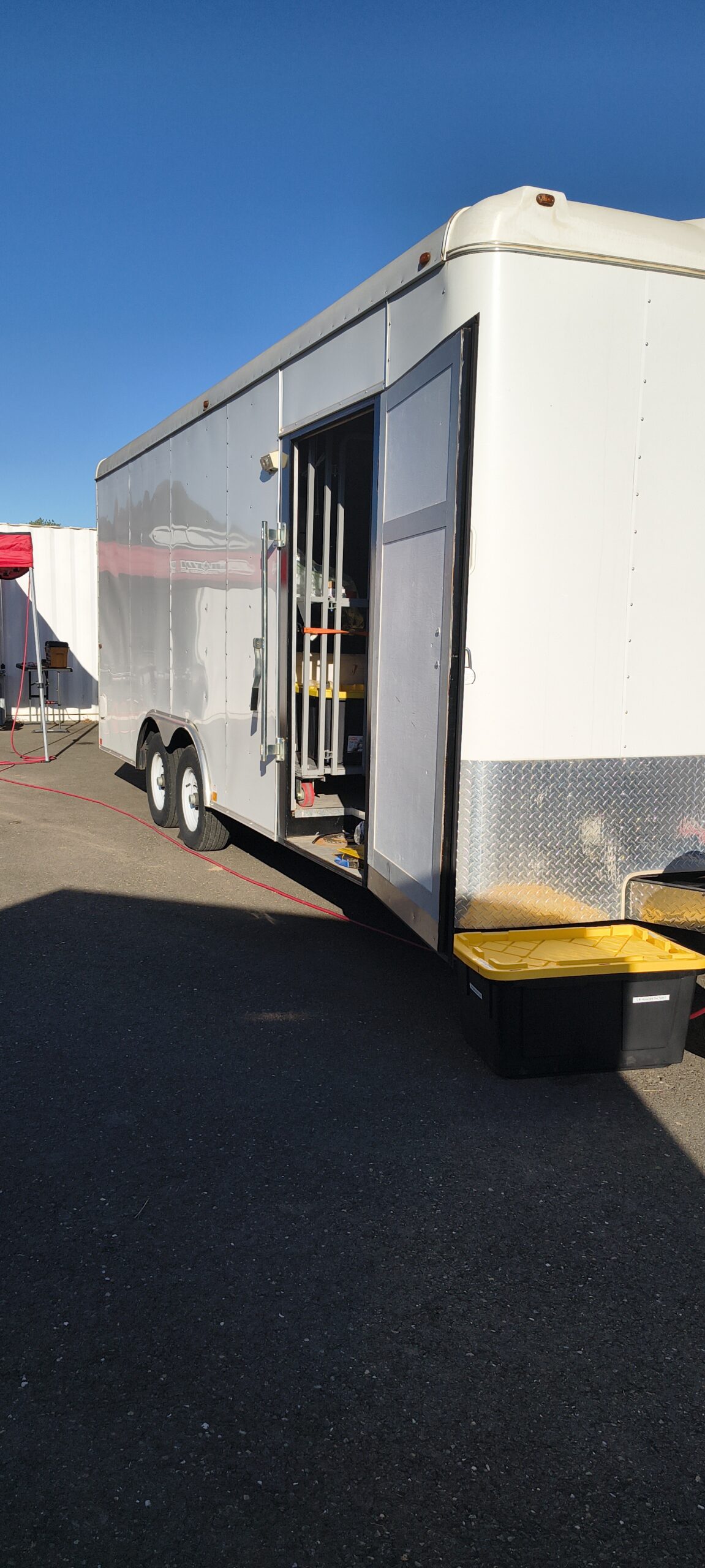 White enclosed trailer with an open storage compartment for karting transport support