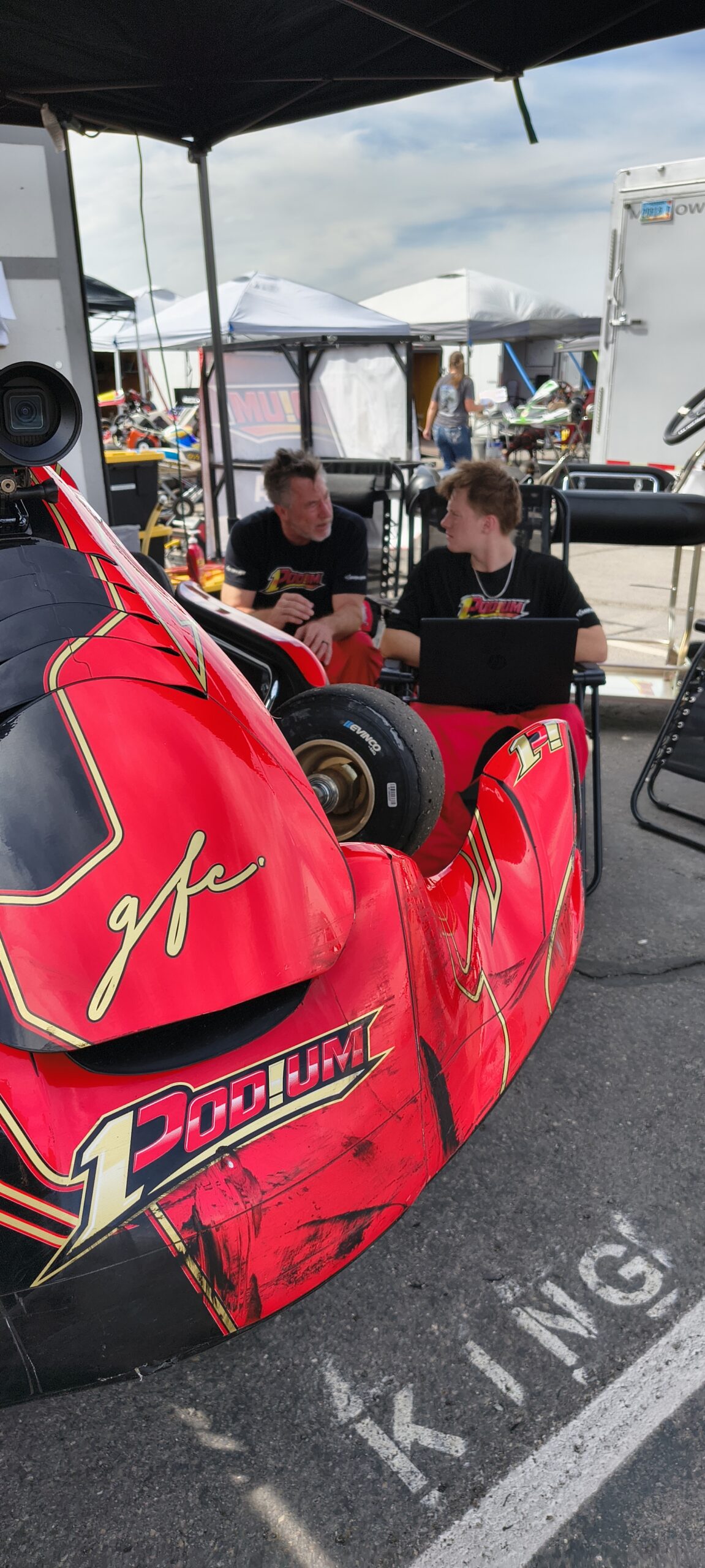 Red-and-black open-wheel race car in the paddock