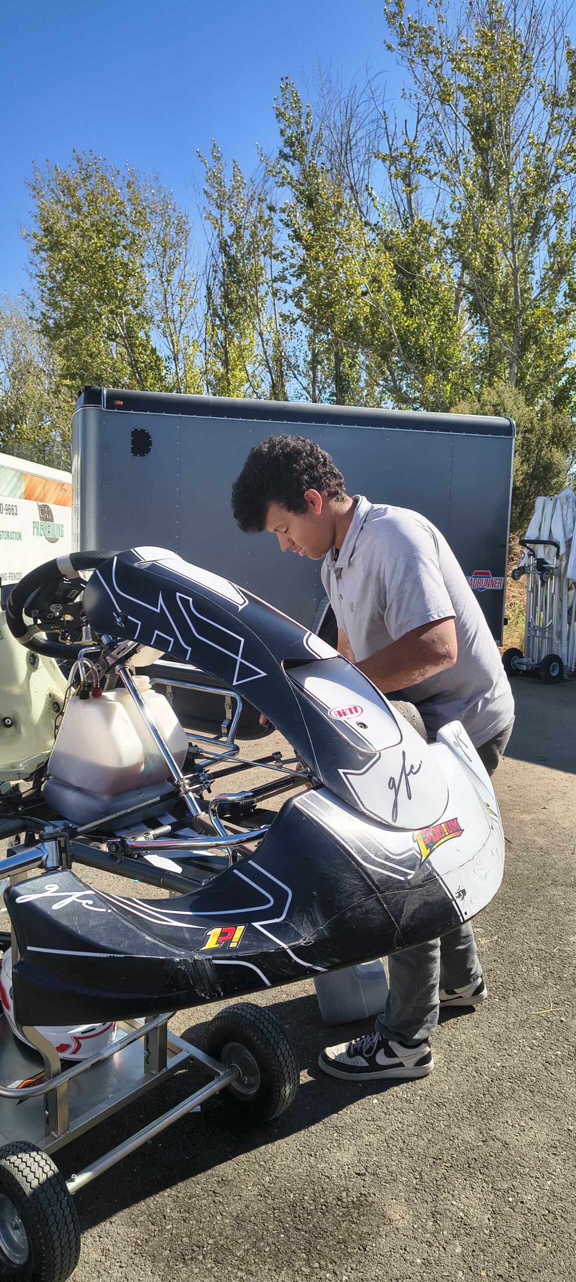 Person working on a go-kart beside a trailer